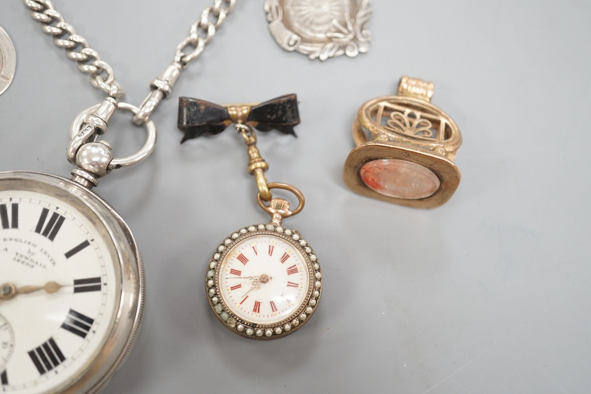 A George V silver open faced lever pocket watch, by A. Yewdall, Leeds, on a silver albert hung with silver medallions, two Swiss white metal and enamel fob watches, gilt fob seal, etc.
